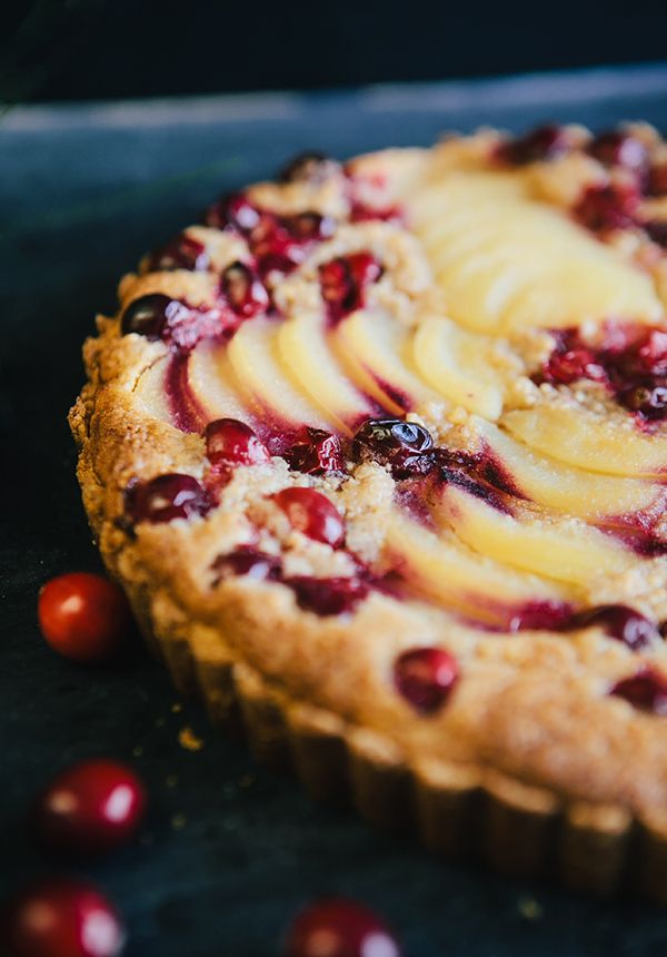 a pie with fruit toppings sitting on top of a table next to cherries