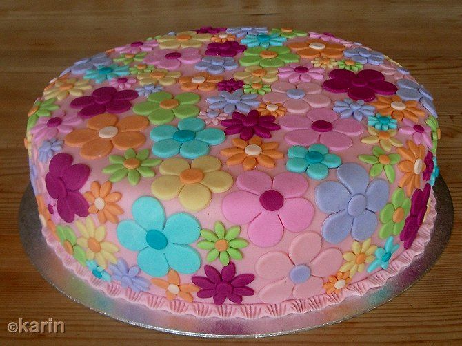 a colorful cake with flowers on it sitting on a table