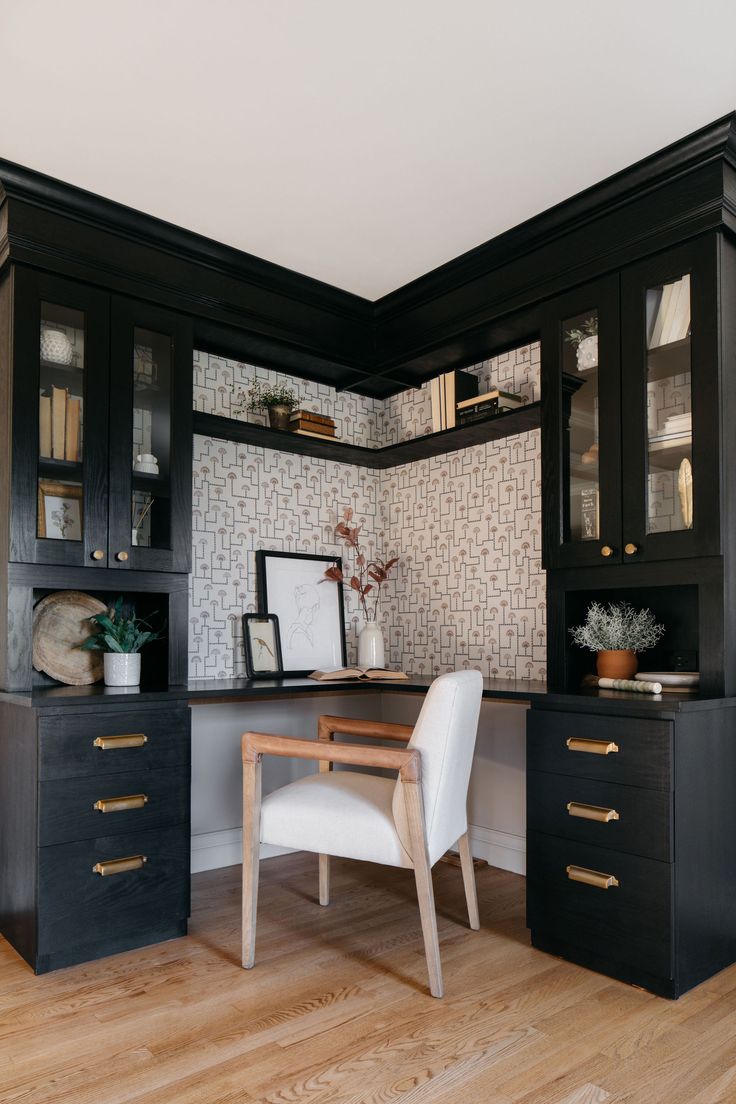 a home office with black cabinets and white chair in the corner, along with wooden flooring