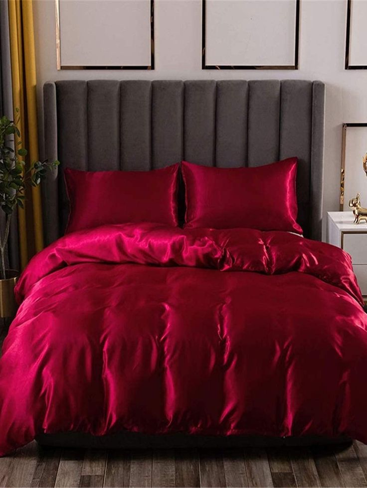 a bed with red sheets and pillows in a room