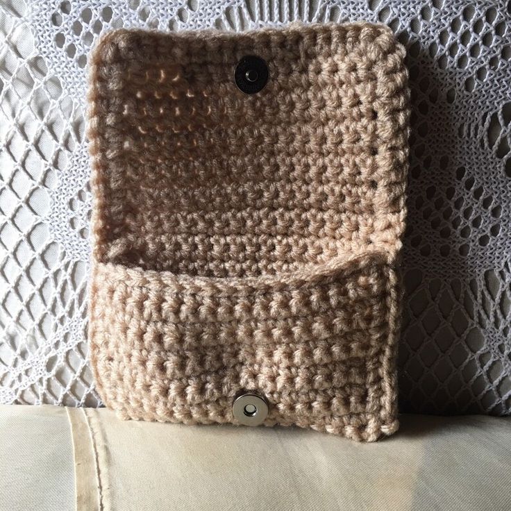 a crocheted purse sitting on top of a white table next to a pillow