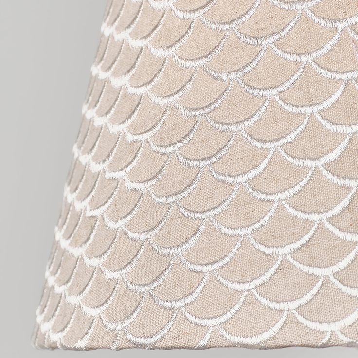 a beige lamp shade with white scales on it