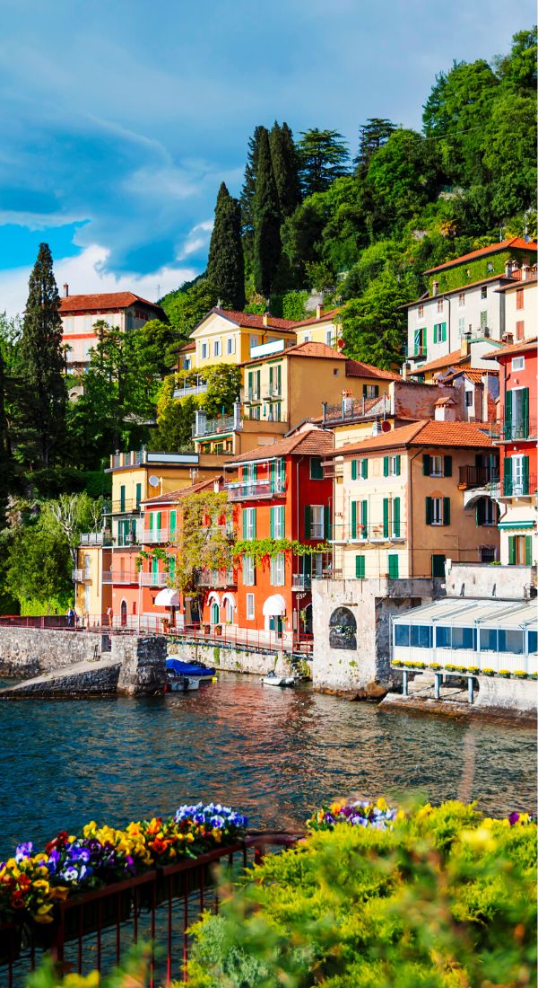 colorful houses line the shore of a lake in italy, with mountains in the background