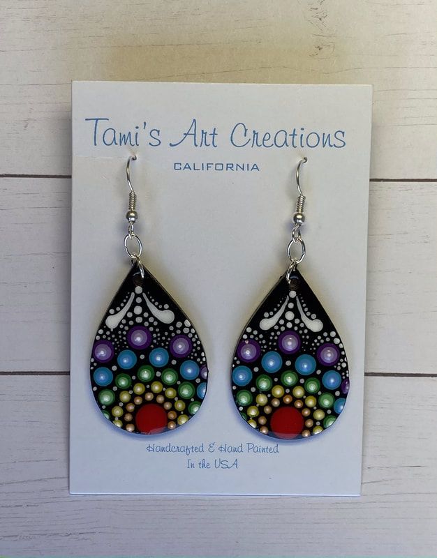 a pair of earrings with colorful beads and pearls on the bottom, hanging from a card