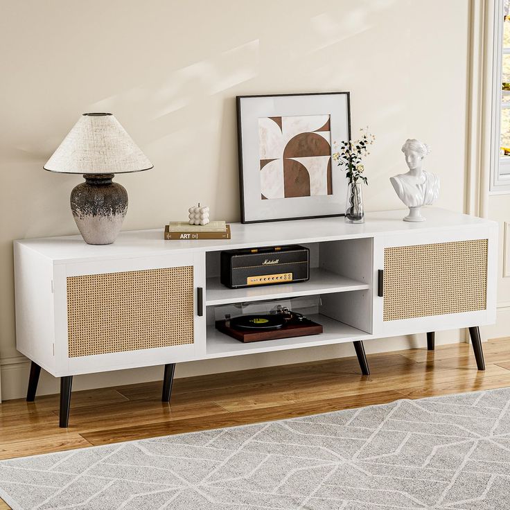 a white entertainment center with wicker doors and drawers in a living room next to a lamp