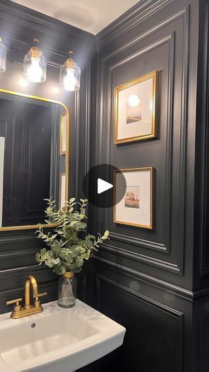 a white sink sitting under a bathroom mirror next to a golden faucet and framed pictures