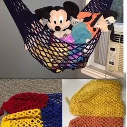 mickey mouse stuffed animal sitting in a hammock with other crocheted items