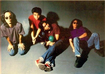 four young men are sitting on the floor with one holding a bowling ball in his hand