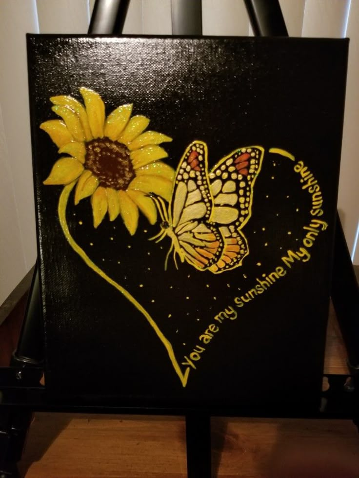 a black bag with sunflowers and a butterfly painted on the side, sitting on a table