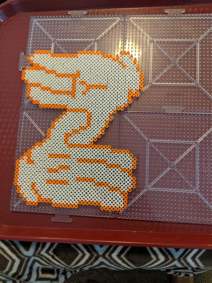 an orange and white pixel art piece sitting on top of a red tray