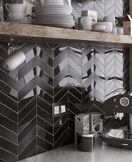 a kitchen with black and white tile backsplashing, coffee maker and cups on the counter