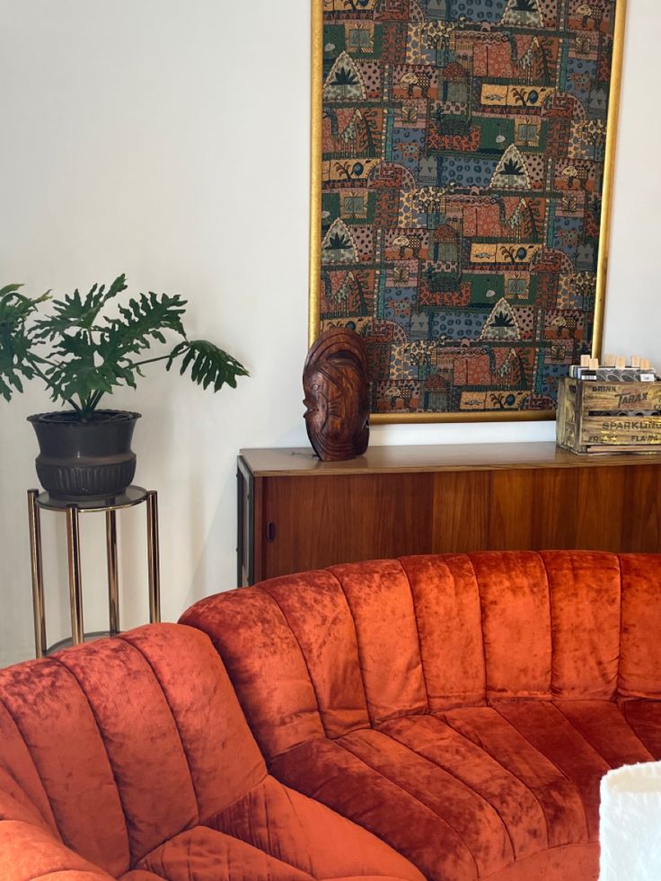 a living room with an orange couch and potted plant