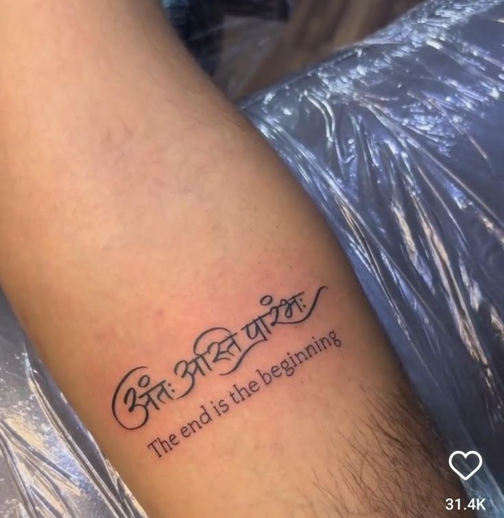 a tattoo saying the end is the beginning on someone's left arm and leg