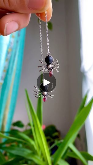 a person is holding up a necklace with a spider on it and beads in the middle