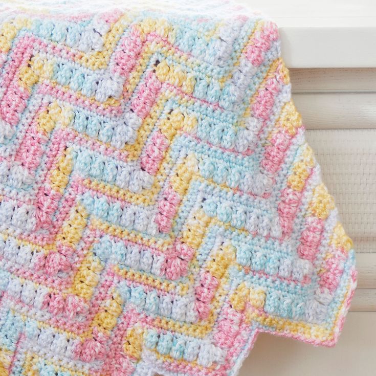 a crocheted blanket hanging on the side of a window sill