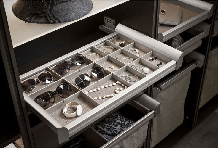 an open drawer with many pairs of sunglasses and jewelry in it on top of a counter