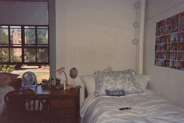 a bed sitting next to a window in a room with pictures on the wall above it