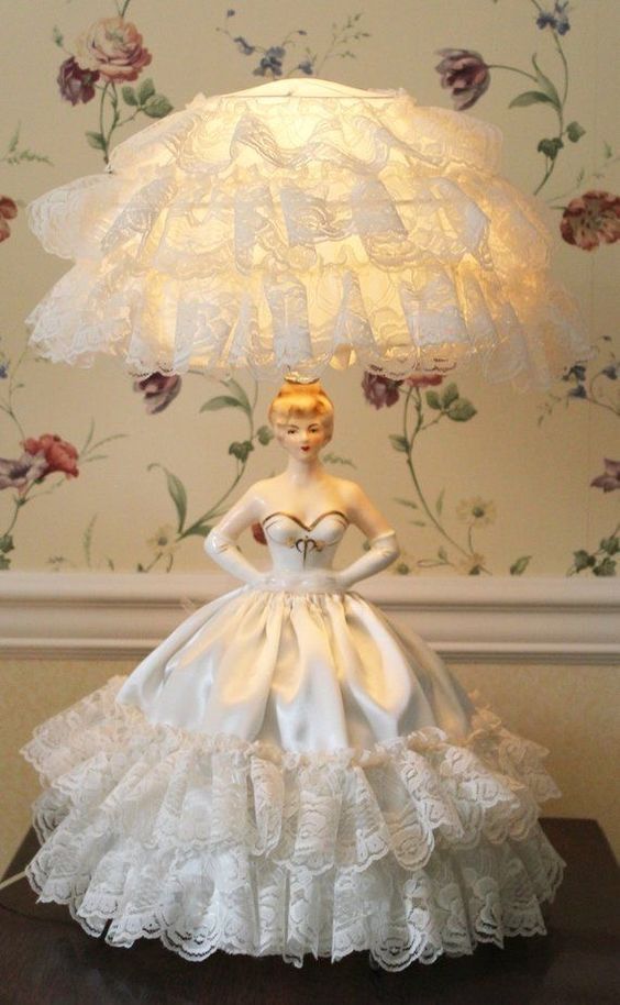 a lamp that is sitting on top of a table with a woman's dress on it