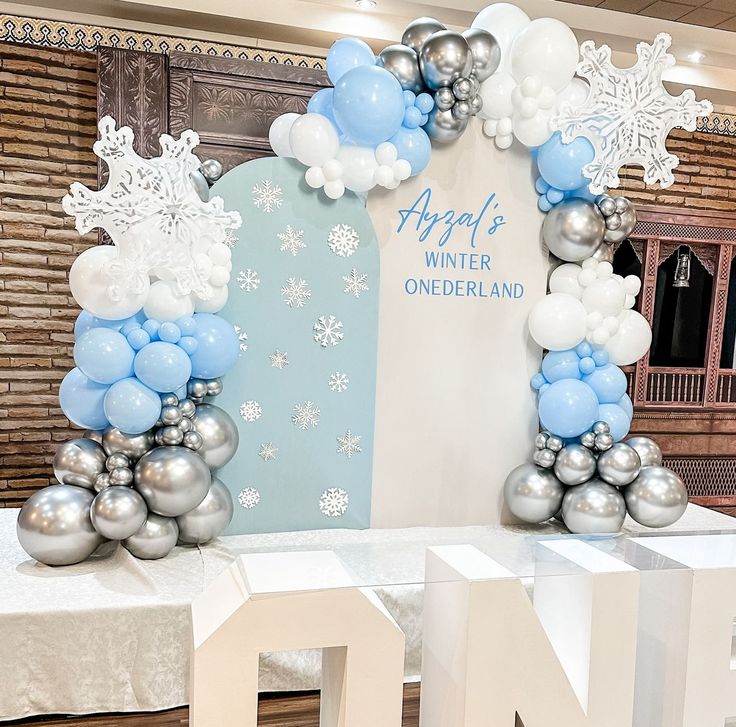 an arch made out of balloons and snowflakes is on display at a winter wonderland birthday party