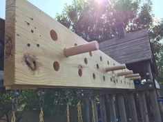 a wooden structure with holes and chains hanging from it's sides in the sun