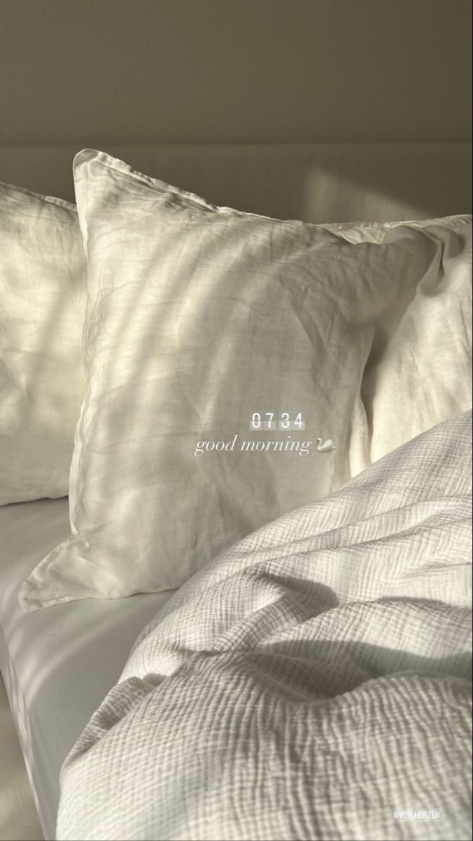 two white pillows sitting next to each other on top of a bed covered in sheets