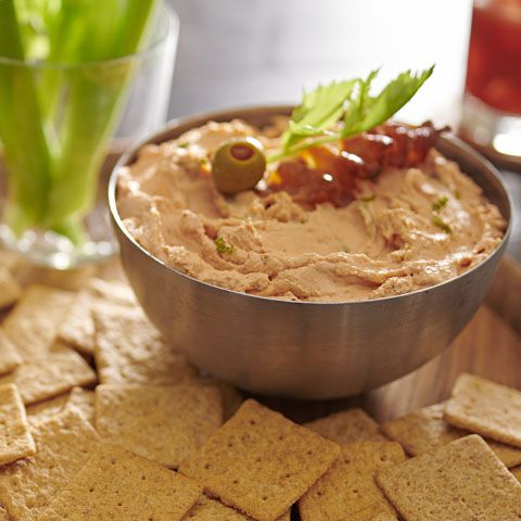 a metal bowl filled with hummus and crackers