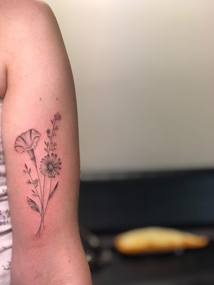 a woman's arm with a flower tattoo on the left side of her arm