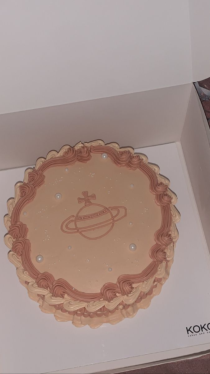 an open box with a cake in the shape of a saturn on it's side