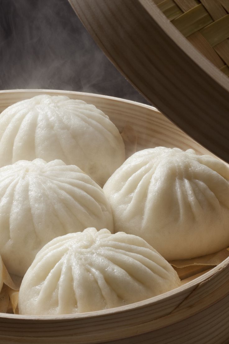 steamed dumplings in a bamboo steamer basket with steam rising from the top and bottom