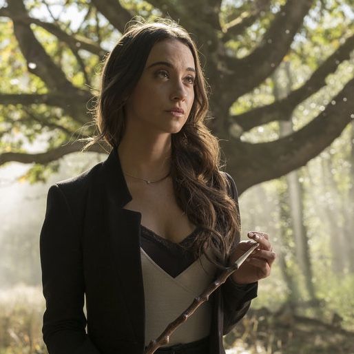 a woman with long hair holding a wand in her hand and looking off into the distance