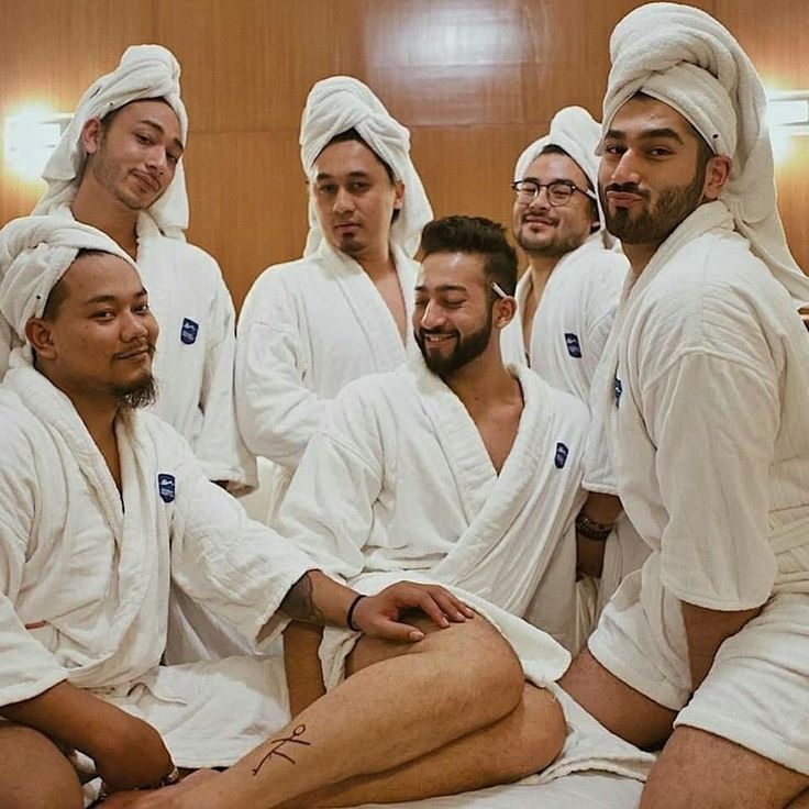 a group of men sitting on top of a bed wearing white robes and head coverings