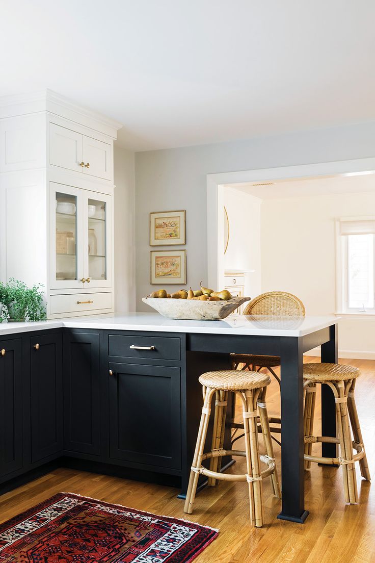 a kitchen with black cabinets and white counter tops, two stools in front of the island