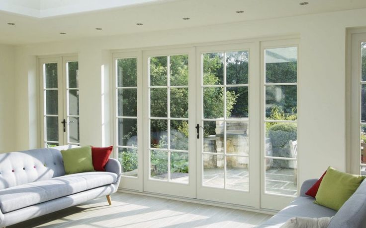 a living room filled with white furniture and lots of windows on top of each other