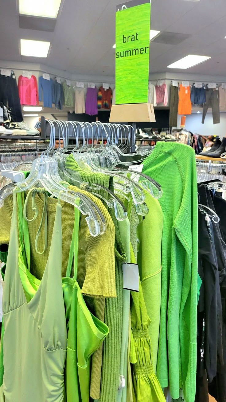 there are many shirts hanging on the rack in this store, and one is green