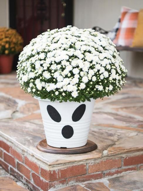 a white flower pot sitting on top of a brick floor