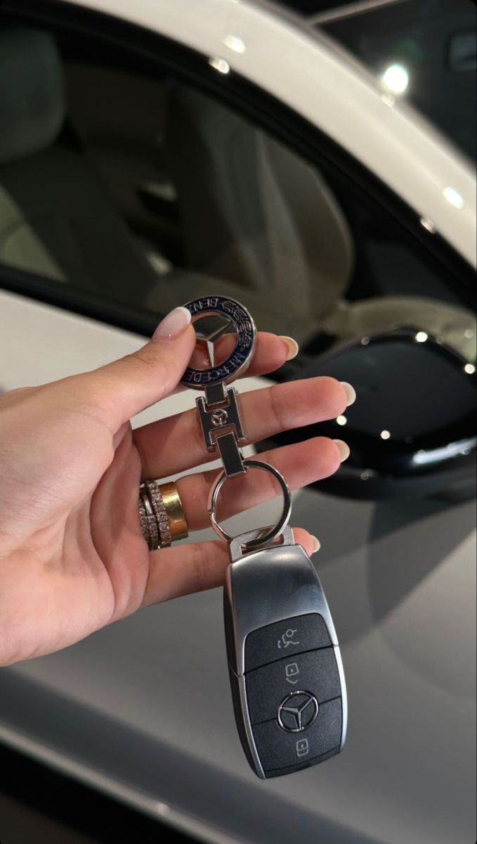 a person holding two keys in front of a car with a key chain attached to it