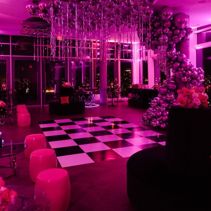 a room with black and white checkerboard flooring, balloons and chandeliers