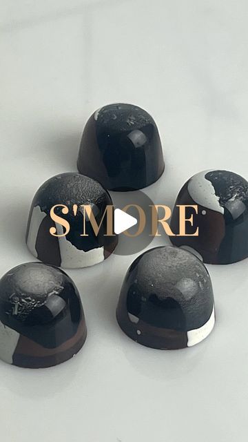 five black and white chocolates with the word smore in gold on it's side