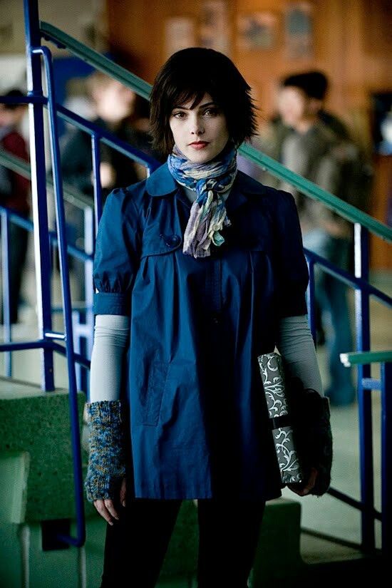 a woman standing in front of some stairs with her hand on her hip and wearing gloves