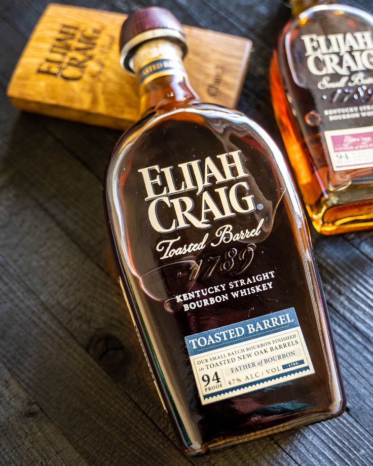 two bottles of eliah craig blended bourbon on a wooden table with labels