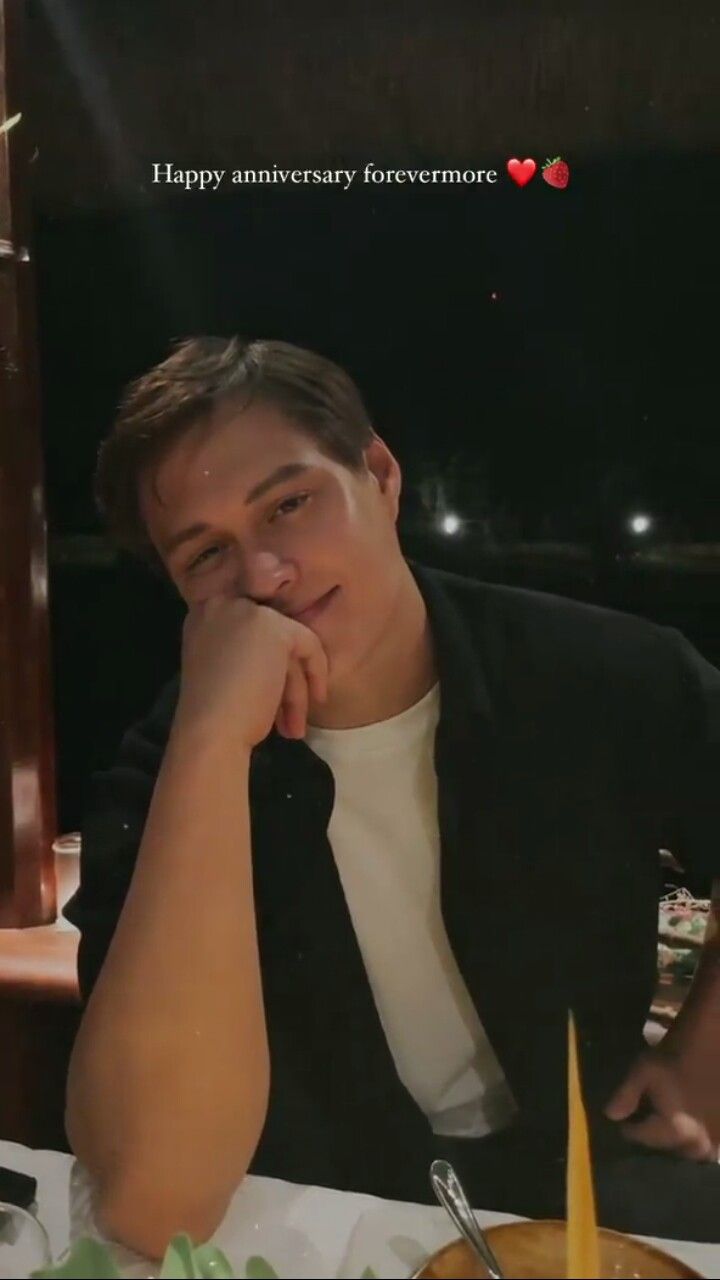 a man sitting at a table in front of a plate of food with his hand on his chin