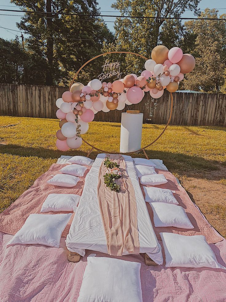 a table set up for a party with pink and white balloons on the top, along with other decorations