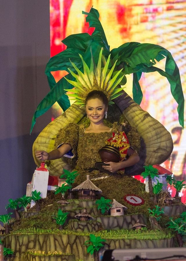 a woman dressed in grass sitting on top of a table