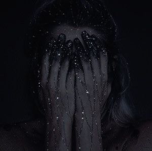 black and white photograph of a woman covering her face with her hands in front of her face