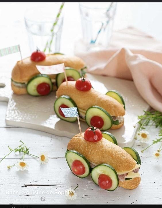 cucumber sandwiches with tomatoes and cherries are arranged in the shape of cars