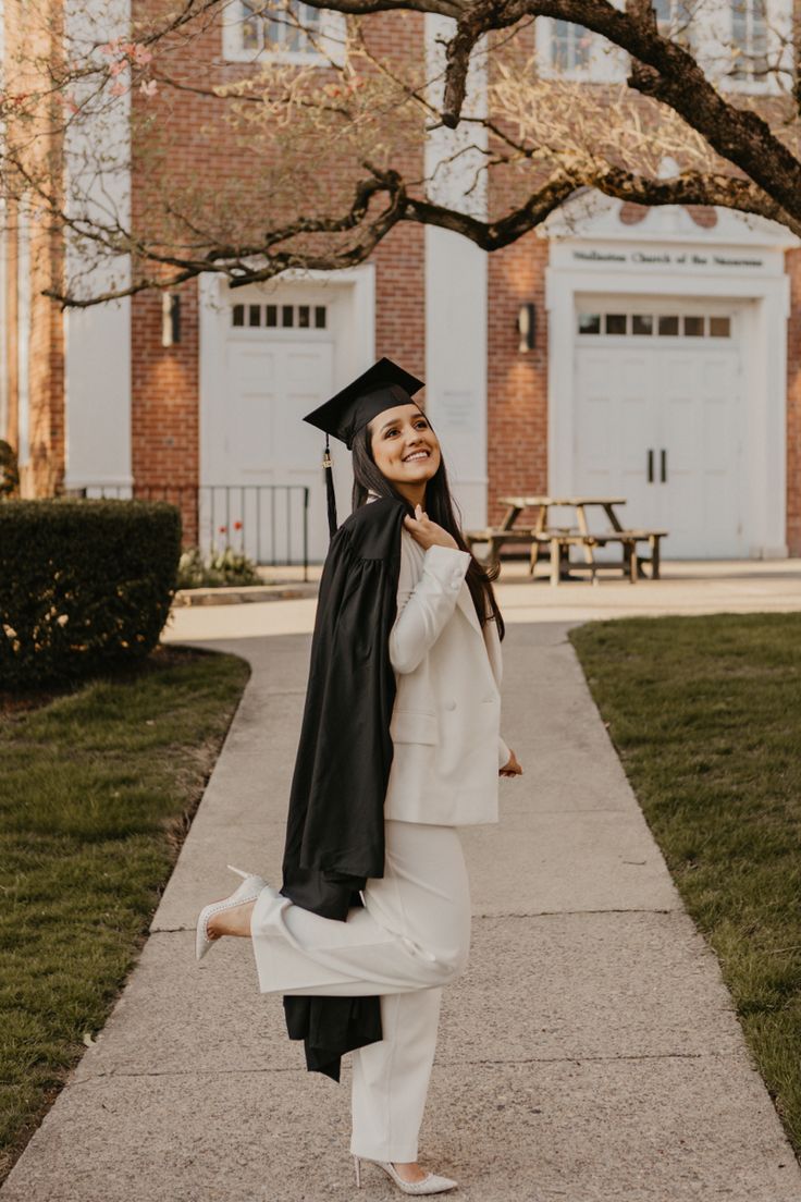 a woman wearing a graduation cap and gown is walking down the sidewalk in front of a building