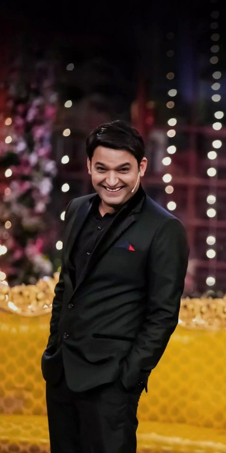 a smiling man in a black suit and red tie