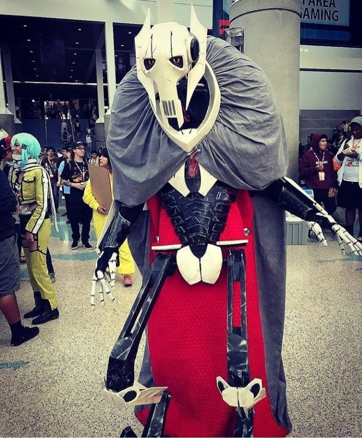 a costumed man in a red dress and mask is posing for the camera at an airport