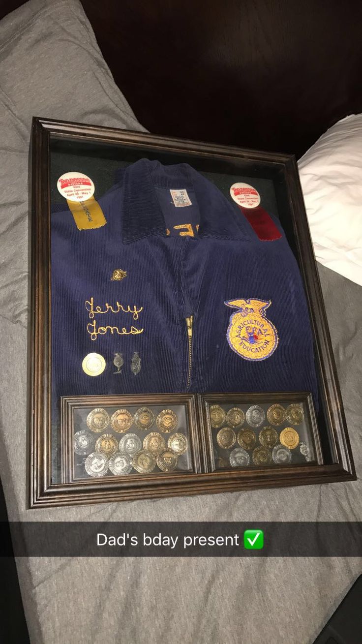 a framed display case with buttons and badges on it's sides, containing two polo shirts