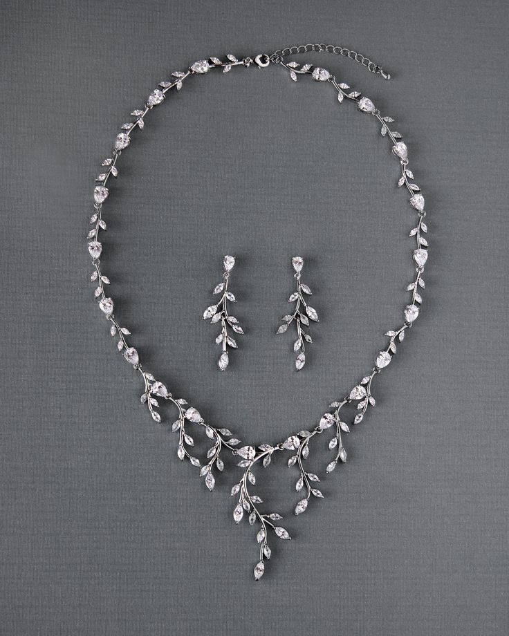 a necklace and earring set is shown on a gray background with silver leaves in the center